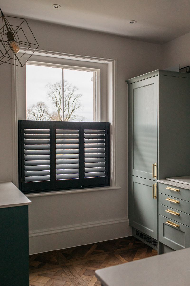 Charcoal café style shutters in a sage-green kitchen