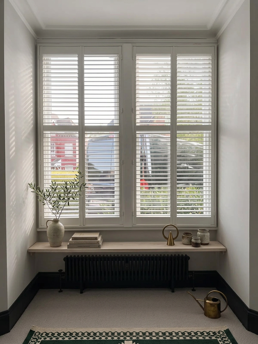 White full-height plantation shutters above a window shelf in a bright Newcastle alcove